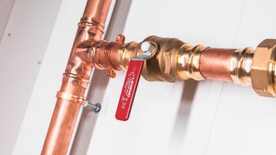 Copper water line with a press tee and a red-handled shutoff valve installed by Black Forest Plumbing