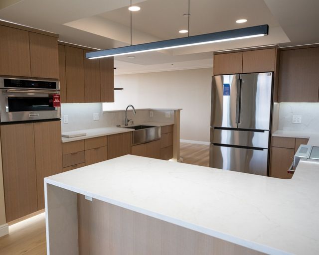 Finished kitchen with a stainless farmhouse sink, pull-down faucet and stone counters